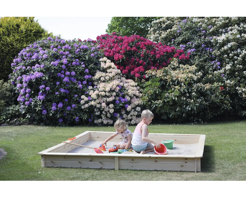 Zwei Kinder spielen in einem Sandkasten aus Holz im Garten