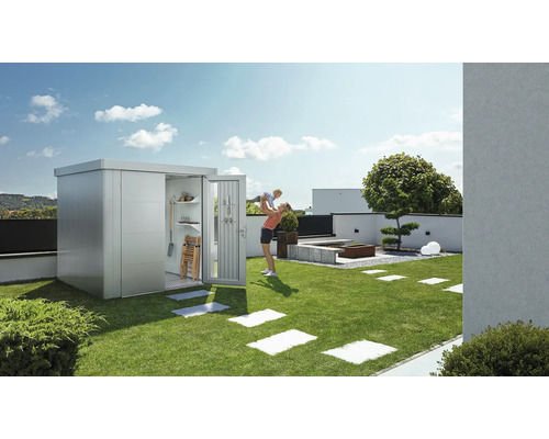 Gartenszene mit Gerätehaus, Rasenfläche und Mutter mit Kind