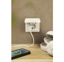 Aufputzsteckdose mit USB-Anschluss und einem Ladekabel, das mit einem Smartphone verbunden ist.