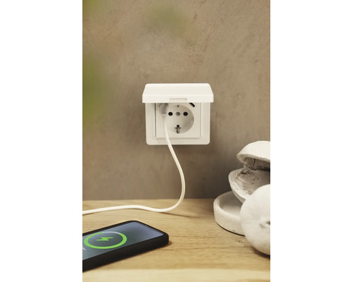 Aufputzsteckdose mit USB-Anschluss und einem Ladekabel, das mit einem Smartphone verbunden ist.
