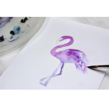 Aquarellmalerei eines Flamingos auf Papier mit Pinsel und Farbpalette