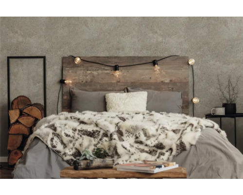 Dekoratives Schlafzimmer mit Holzkopfende, Lichterkette, Kissen und Tagesdecke