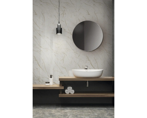 Badezimmer mit Waschtisch, Spiegel, Lampe und Wandfliesen in Marmoroptik.