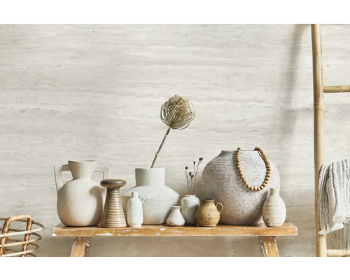 Dekorative Keramikvasen auf einem rustikalen Holztisch, ergänzt durch eine Bambusleiter mit Textilien und eine Wand mit horizontalem Muster.