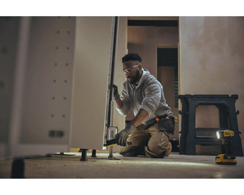 Handwerker justiert Küchenschrank mit Nivellierwerkzeug in heller Umgebung.