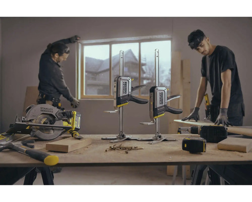 Szene einer Werkstatt mit Werkzeugen und zwei Handwerkern bei der Arbeit an einem Fenster.