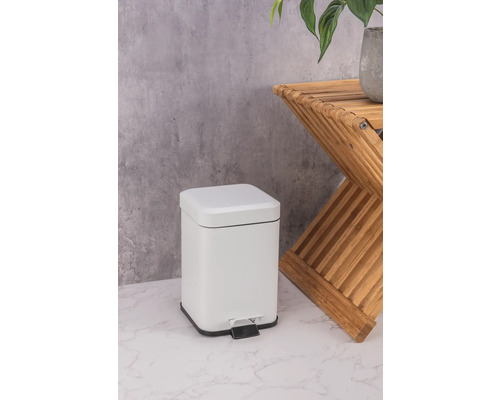 Weißer Tretabfalleimer aus Metall neben einem Beistelltisch aus Holz