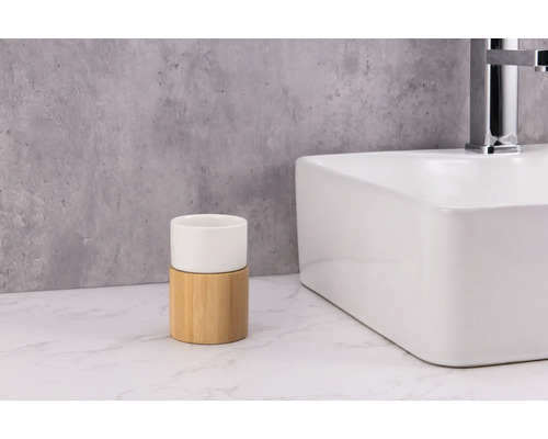 Zahnputzbecher aus Keramik und Bambus neben einem Waschbecken