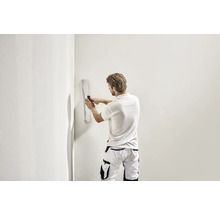 Handwerker glättet Wand mit Flächenspachtel