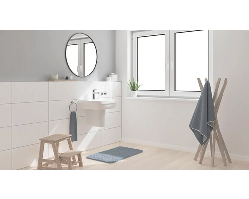Helles Badezimmer mit Waschtisch, Spiegel, Handtuchhalter und Badematte