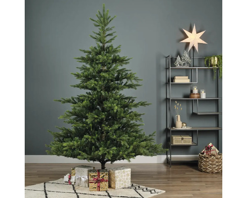 Geschmückter Weihnachtsbaum mit Geschenken in einem Wohnzimmer.