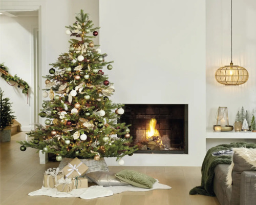 Weihnachtsbaum mit Ornamenten und Geschenken im Wohnzimmer vor Kamin