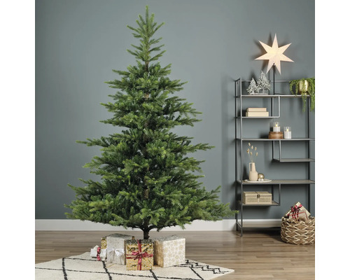 Künstlicher Tannenbaum mit Weihnachtsgeschenken auf einem Teppich im Raum.