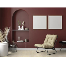 Wohnzimmer mit Sessel, Dekoration und Bilderrahmen an einer dunkelroten Wand