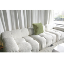 Weißes modulares Sofa mit Kissen und Strukturbezug vor einem Fenster mit Vorhängen