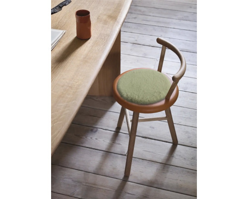 Holzhocker mit rundem Sitzkissen und Rückenlehne neben einem Tisch.