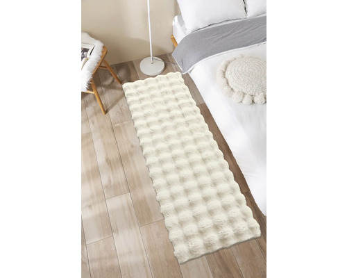 Flauschiger Teppich im Schlafzimmer neben einem Bett und einer Lampe.