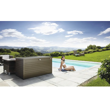 Szene mit einer Aufbewahrungsbox aus Metall neben einem Pool, umgeben von Gartenmöbeln und einer Frau, die im Wasser sitzt.