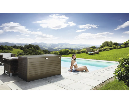 Szene mit einer Aufbewahrungsbox aus Metall neben einem Pool, umgeben von Gartenmöbeln und einer Frau, die im Wasser sitzt.