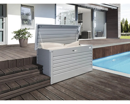 Auf einer Holzterrasse steht eine geöffnete Aufbewahrungsbox mit Kissen.