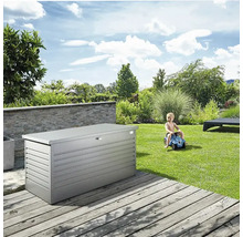 Graue Gartenbox auf einer Holzterrasse, im Hintergrund ein spielendes Kind und eine grüne Gartenlandschaft