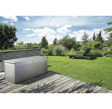 Gartenlandschaft mit einer Aufbewahrungsbox aus Metall und einer Sonnenliege auf einem Rasen