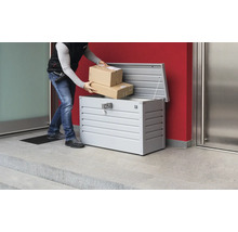 Paketzusteller legt Pakete in eine Paketbox aus Metall