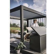Mann verstaut Kissen in einer Aufbewahrungsbox im Außenbereich unter einer Pergola.