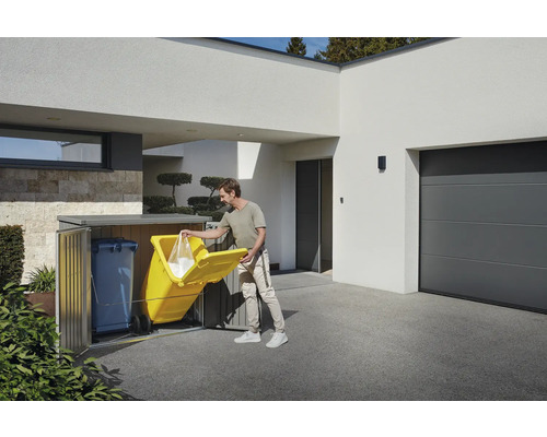 Mülltonnenbox im Außenbereich mit Mann, der eine Mülltüte in eine gelbe Mülltonne wirft