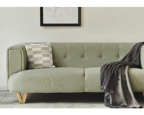 Helles Sofa mit Kissen und Decke im Wohnzimmer