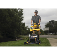 Mann bedient gelben Rasenmäher der Marke DeWalt im Garten.