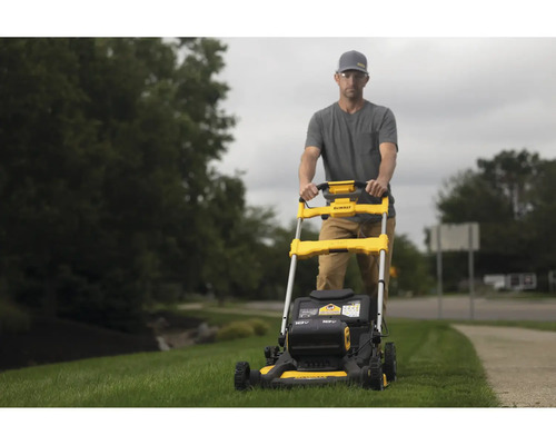 Mann bedient gelben Rasenmäher der Marke DeWalt im Garten.