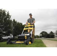 Mann schiebt einen gelben und schwarzen Rasenmäher im Garten.