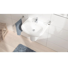 Helles Badezimmer mit weißem Waschbecken, Armatur, Handtuchhalter und Teppich