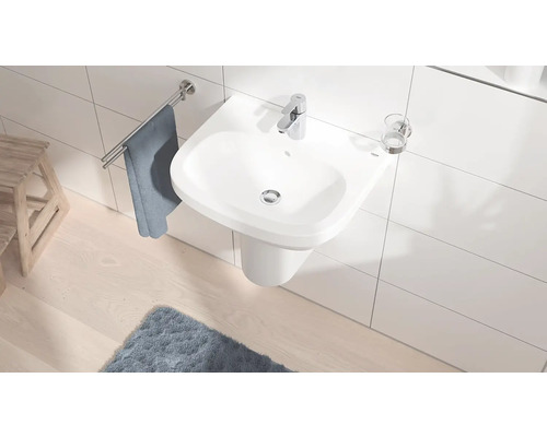 Helles Badezimmer mit weißem Waschbecken, Armatur, Handtuchhalter und Teppich