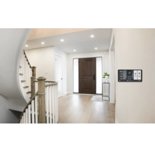 Helle Eingangshalle mit Treppe, Haustür und Smart Home Steuerung an der Wand.