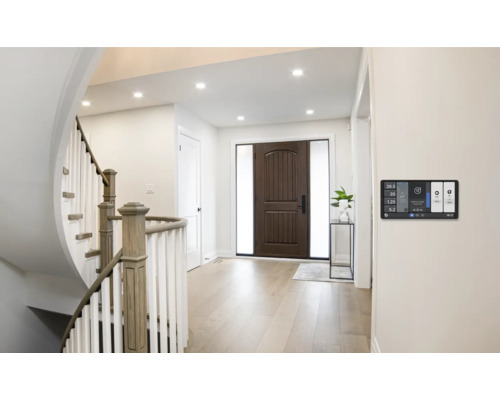 Helle Eingangshalle mit Treppe, Haustür und Smart Home Steuerung an der Wand.