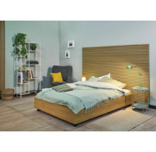 Helles Schlafzimmer mit Bett, Nachttisch, Regal und Sessel