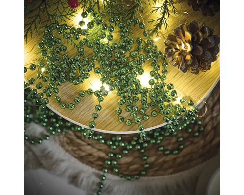Dekoration mit Tannenzweigen, Lichterkette, Tannenzapfen und grüner Kugelkette