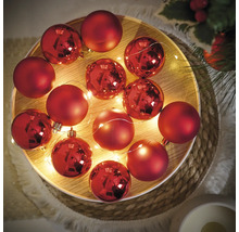 Dekorative rote Weihnachtskugeln mit Lichterkette auf einem Tablett