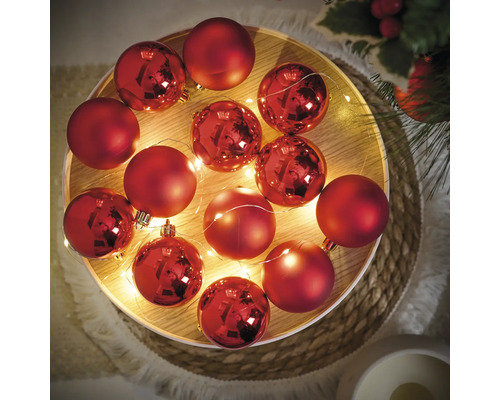 Dekorative rote Weihnachtskugeln mit Lichterkette auf einem Tablett