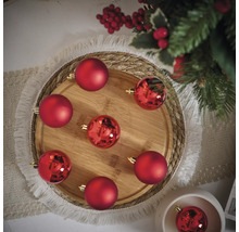 Dekorative Anordnung von roten Weihnachtskugeln auf einem Holztablett