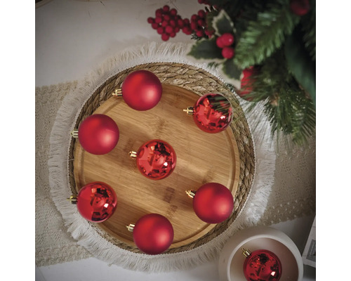 Dekorative Anordnung von roten Weihnachtskugeln auf einem Holztablett