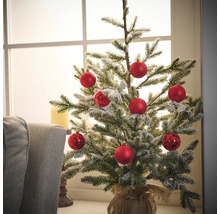 Dekorierter kleiner Weihnachtsbaum mit roten Kugeln in Jutesack