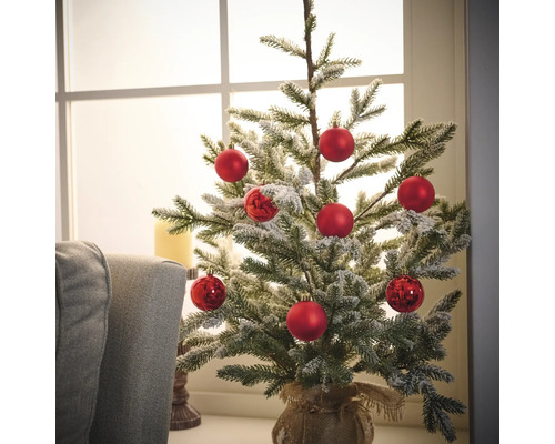 Dekorierter kleiner Weihnachtsbaum mit roten Kugeln in Jutesack