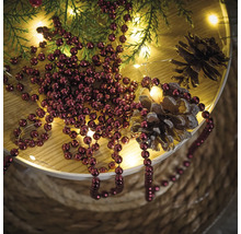 Dekoration mit Weihnachtskugeln, Tannenzweigen, Lichterkette und Tannenzapfen auf einem Tisch