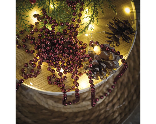 Dekoration mit Weihnachtskugeln, Tannenzweigen, Lichterkette und Tannenzapfen auf einem Tisch