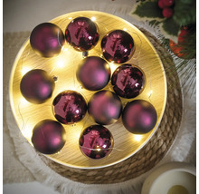 Dekorative violette Weihnachtskugeln mit Lichterkette auf einem Tablett