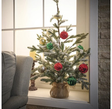 Dekorierter künstlicher Weihnachtsbaum auf Fensterbank
