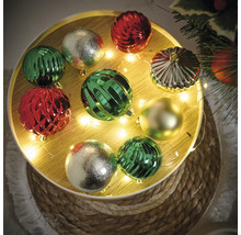 Dekorative Weihnachtskugeln in Grün, Rot und Gold auf einem runden Tablett mit Lichterkette.